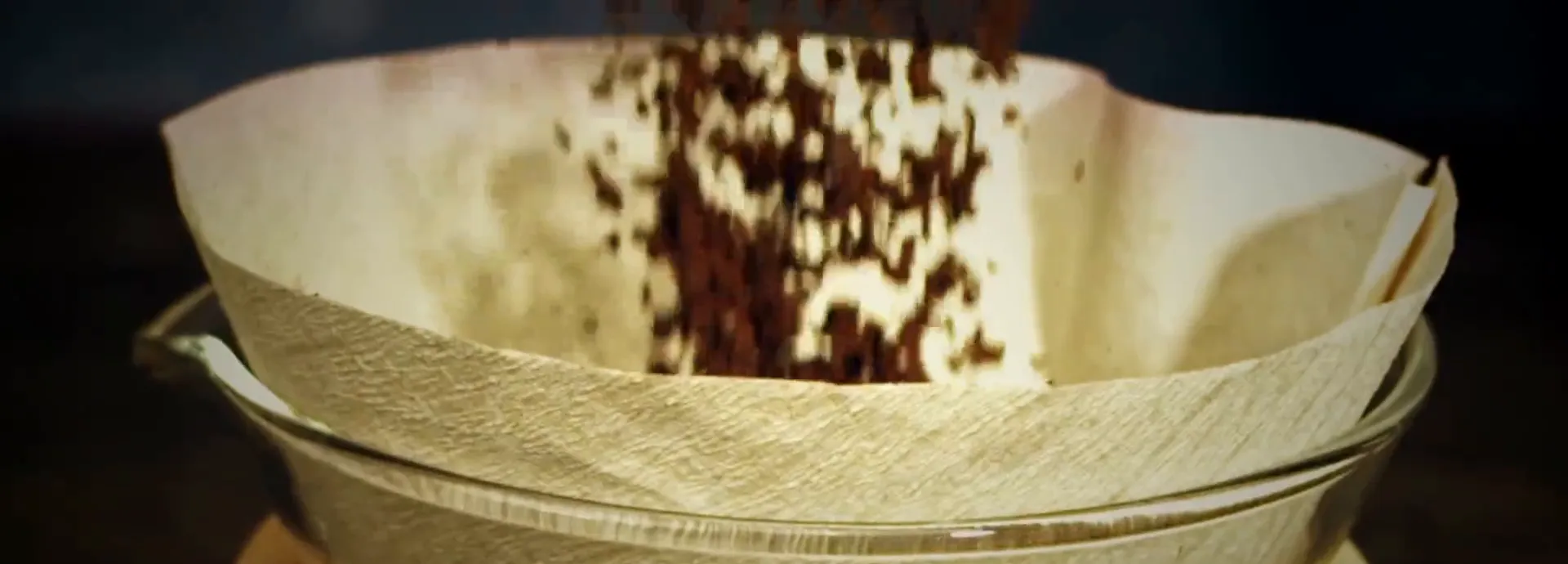Ground coffee falling into a paper filter
