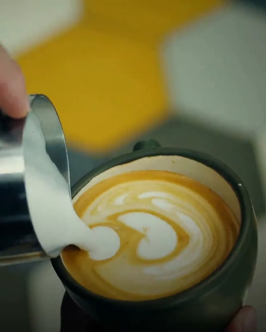Milk being poured into a flat white, forming a pattern