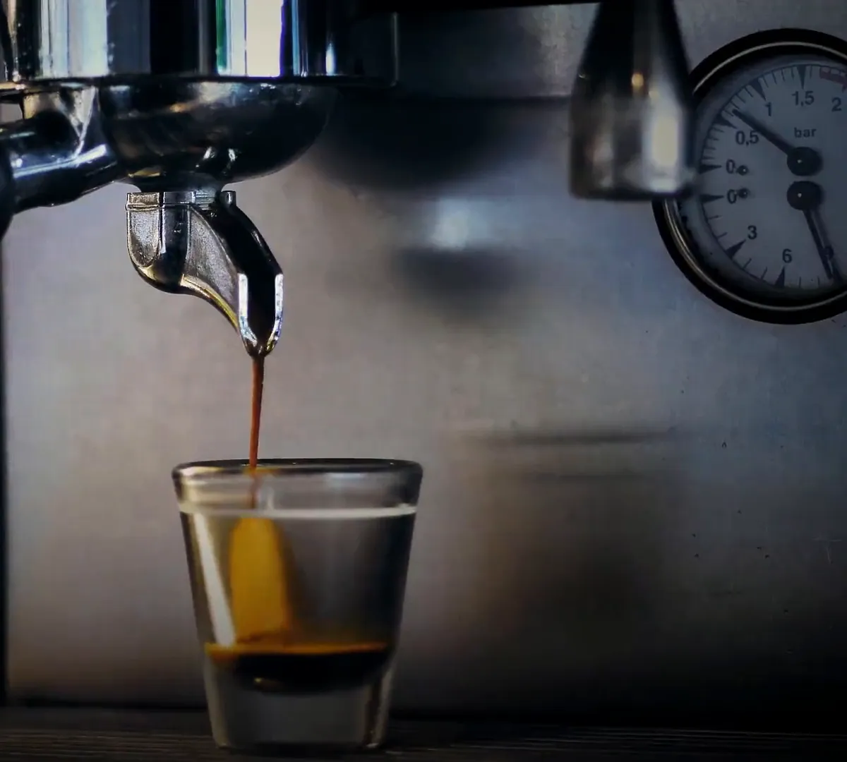 An espresso machine pulling a shot into a small glass